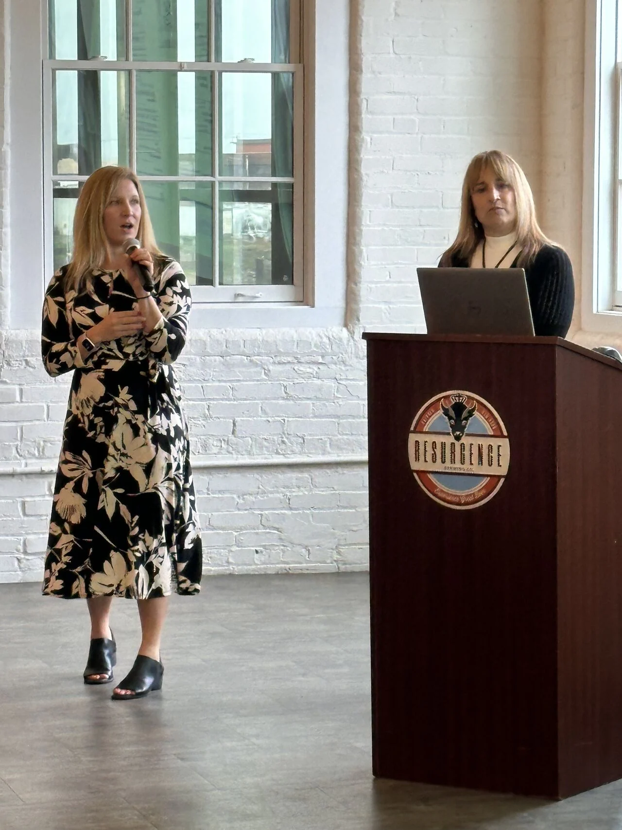 Two presenters address the Partner Breakfast beside a podium.